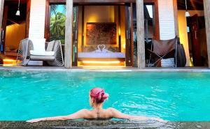 a woman sitting in the water in a swimming pool at Kaleydo Villas in Gili Trawangan
