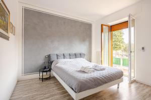 a white bedroom with a bed and a large window at Garda Art&Lake in Peschiera del Garda