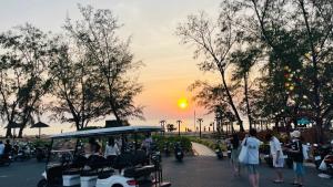 eine Gruppe von Menschen, die um einen Bus mit Sonnenuntergang stehen in der Unterkunft Hotel Amber View Beach Vinwonder Safari VietNam in Phu Quoc