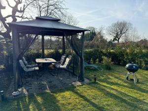 a gazebo with chairs and a table and a grill at Ferienwohnung am See Dillich - Hunde willkommen - Eigener eingezäunter Garten - Ruhige Lage in Borken