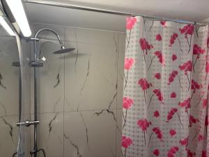 a shower curtain with pink flowers on it in a bathroom at rosi rhodos in Rhodes Town