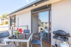 een terras met een tafel en stoelen op een balkon bij Breathtaking Clifftop Ocean Views from Unit 12 in Eden