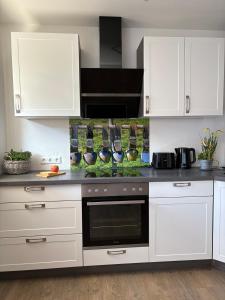 a kitchen with white cabinets and a stove top oven at Alm Studio 22 - Thymian - Ferienwohnung in Fischen in Fischen