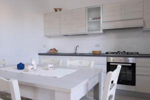 a white kitchen with a white table and chairs at Guest House in Mercatello