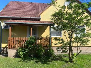 a yellow house with a wooden fence in the yard at Garda Apartman in Balatonfenyves