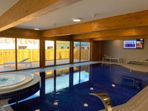 a swimming pool in a building with a large ceiling at Premium Resort Skalka - wellness výhody in Železná Ruda