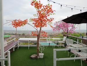 a tree on a balcony with tables and an umbrella at บ้านไร่เก็บตะวันโฮมสเตย์น้ำหนาว in Ban Phu Hi