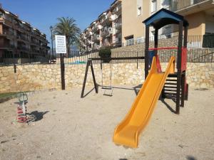 a playground with a slide and a swing set at Precioso dúplex con vistas al mar y piscina in Les Cases d'Alcanar