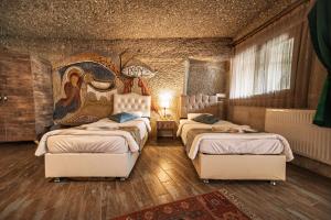 ギョレメにあるAdelya Cave Hotelのベッドが2つあり、壁に絵が飾られた寝室