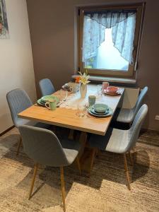 a dining room table with chairs and a table with plates and glasses at Gemütliches Ferienhaus nahe Dinkelsbühl in Dürrwangen