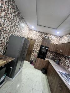 a kitchen with a refrigerator and a tile wall at Luxury 4BR Apt 5Min to LCC with Pool in Secured Estate in Ibeju