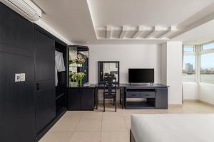 a living room with a desk and a television at Kay Han Riverfront Hotel Da Nang in Danang