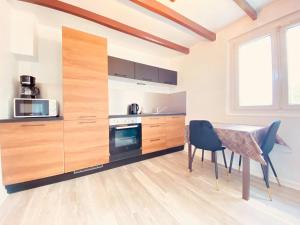 a kitchen with wooden cabinets and a table and chairs at Appartement Cosy avec jardin chaleureux in Laon +19 photos