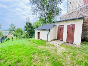 a building with two red doors on a grassy hill at Appartement Cosy avec jardin chaleureux in Laon