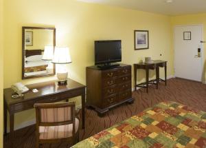 a hotel room with a bed and a desk with a television at Campbell Inn Hotel in Campbell