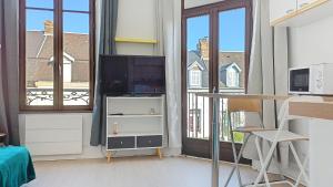 a living room with a tv and a desk and windows at L'opale, studette 4 in Berck-sur-Mer