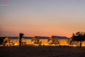 山姆Zostel Sam Desert (Jaisalmer)的日落时分在沙漠中的一排小屋