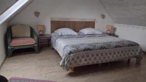a bedroom with a large bed and a chair at La ferme de la Cavalerie in Saint-Gonnery