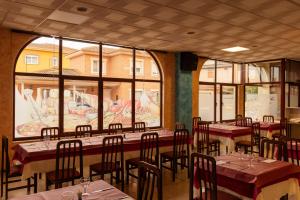 a restaurant with tables and chairs in a room with windows at HOSTAL La MARAVILLOSA DE VALDERAS in Valderas