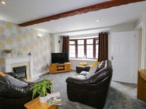 a living room with two leather couches and a television at The Old Surgery in Grange Over Sands