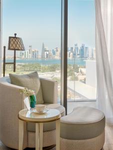 a living room with a table and chairs and a large window at Mandarin Oriental, Doha in Doha
