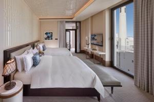 een slaapkamer met twee bedden en een groot raam bij Mandarin Oriental, Doha in Doha