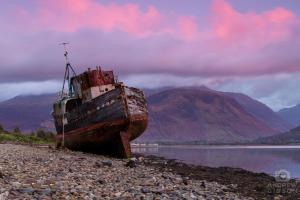 an old boat sitting on the shore of a lake at Rowandell Highland Studio in Fort William +2 photos