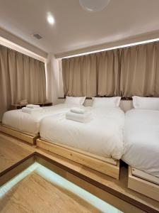 Dos camas en un dormitorio con sábanas blancas. en Ikeda Ueno 401 Quad room, en Tokio 3 fotos más