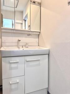 Un baño con un lavabo blanco y un espejo. en Ikeda Ueno 401 Quad room, en Tokio