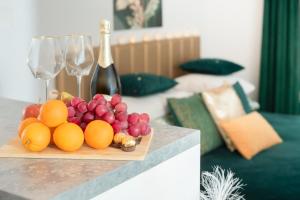 a plate of fruit on a table with wine glasses at Gold Apartments Centrum in Częstochowa