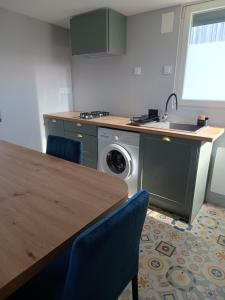 a kitchen with a table and a sink and a washing machine at Le Ch'ti Tonnay in Tonnay-Charente