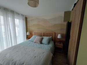 a bedroom with a bed with blue and pink pillows at Le Ch'ti Tonnay in Tonnay-Charente