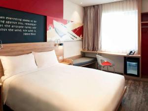 a hotel room with a white bed and a desk at Ibis Saigon Airport in Ho Chi Minh City