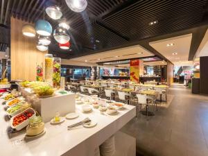 a restaurant with white tables and chairs with food at Ibis Saigon Airport in Ho Chi Minh City