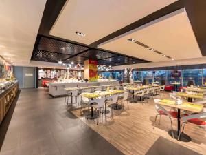 a restaurant with tables and chairs and a bar at Ibis Saigon Airport in Ho Chi Minh City