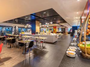 a restaurant with tables and chairs and a cafeteria at Ibis Saigon Airport in Ho Chi Minh City