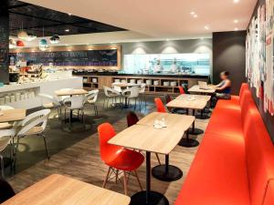 a restaurant with wooden tables and red chairs at Ibis Saigon Airport in Ho Chi Minh City