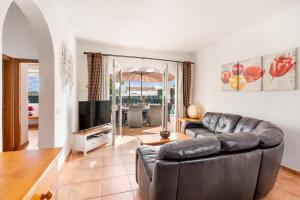 a living room with a leather couch and a television at Villa OCEANA in Cala en Porter