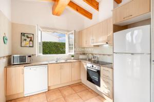 a kitchen with wooden cabinets and a white refrigerator at Villa OCEANA in Cala en Porter