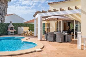 a patio with a swimming pool and a pergola at Villa OCEANA in Cala en Porter