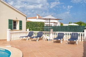 a patio with chairs and an umbrella next to a pool at Villa OCEANA in Cala en Porter