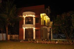 a house with lights on the front of it at night at ecr resorts- pleasant stay farmhouse in Sadras