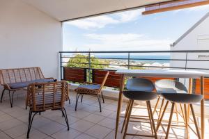 a balcony with chairs and a table and a view of the ocean at Le Petit Coin de LyNa - 3 ÉTOILES - 4 voyageurs in Saint-Pierre