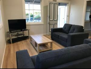 a living room with two blue couches and a television at Eton Cottage - Central Boutique Stay in Toowoomba