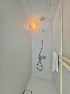 baño blanco con ducha con luz en Ikeda Ueno 501 Quad room Room, en Tokio