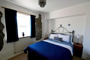 a bedroom with a blue and white bed and a window at Old Bakery Cottage in Mortehoe