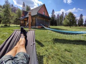 a person laying on a hammock in front of a house at Szałas na szlaku in Witów +56 photos