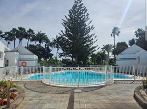 a white fence around a pool with trees and houses at El Caramelito 3 in San Bartolomé