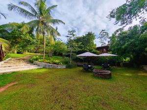a yard with tables and umbrellas on the grass at The Nature Palace Villa in Ahungalla