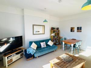 Una sala de estar con un sofá azul y una mesa. en NEW Seabreeze Large Family Apt Sea Views Ventnor, en Ventnor